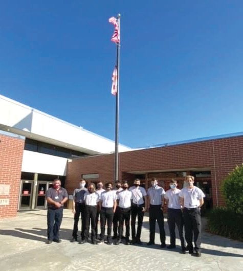 LHS Fire Academy students stand in front of the flagpole at the high school.